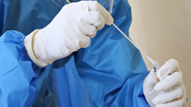 A lab worker takes a swab test. Photo credit: Mufid Majnun